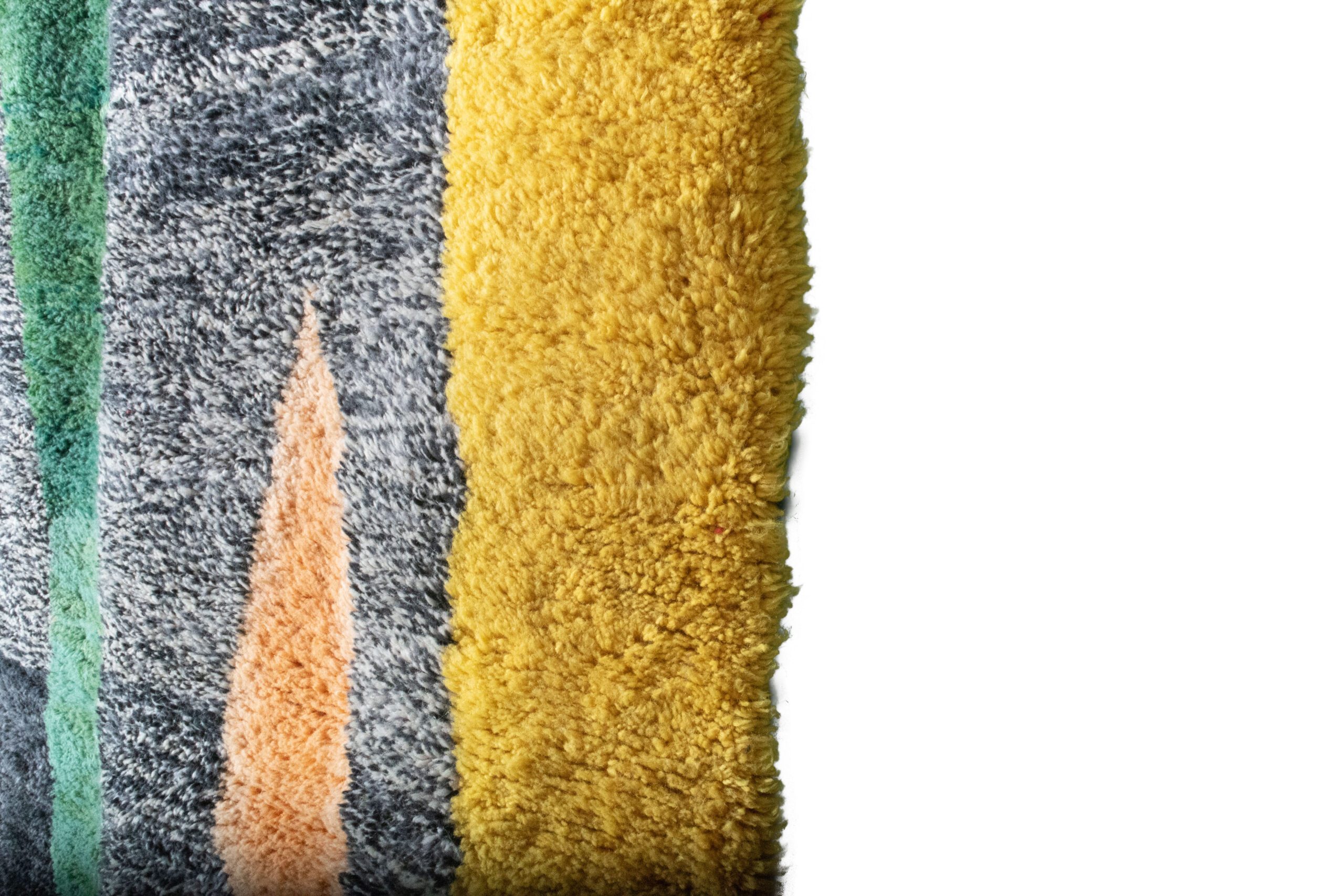 a pile of colorful rugs on a white background. VINX11_BK-39_W-40_YL-16_GR-10_GR-11_OR-24 (3)