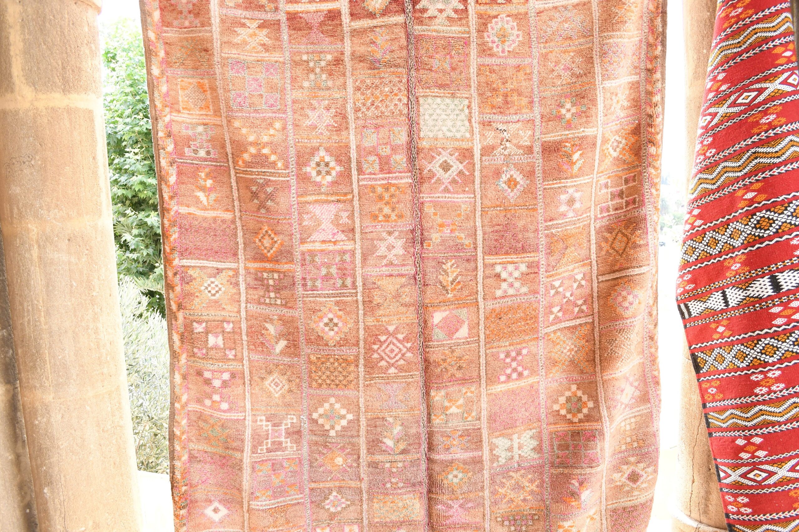 a red and pink patterned moroccan rug hanging on a wooden pole. il_fullxfull.6017466424_1y0o.jpg