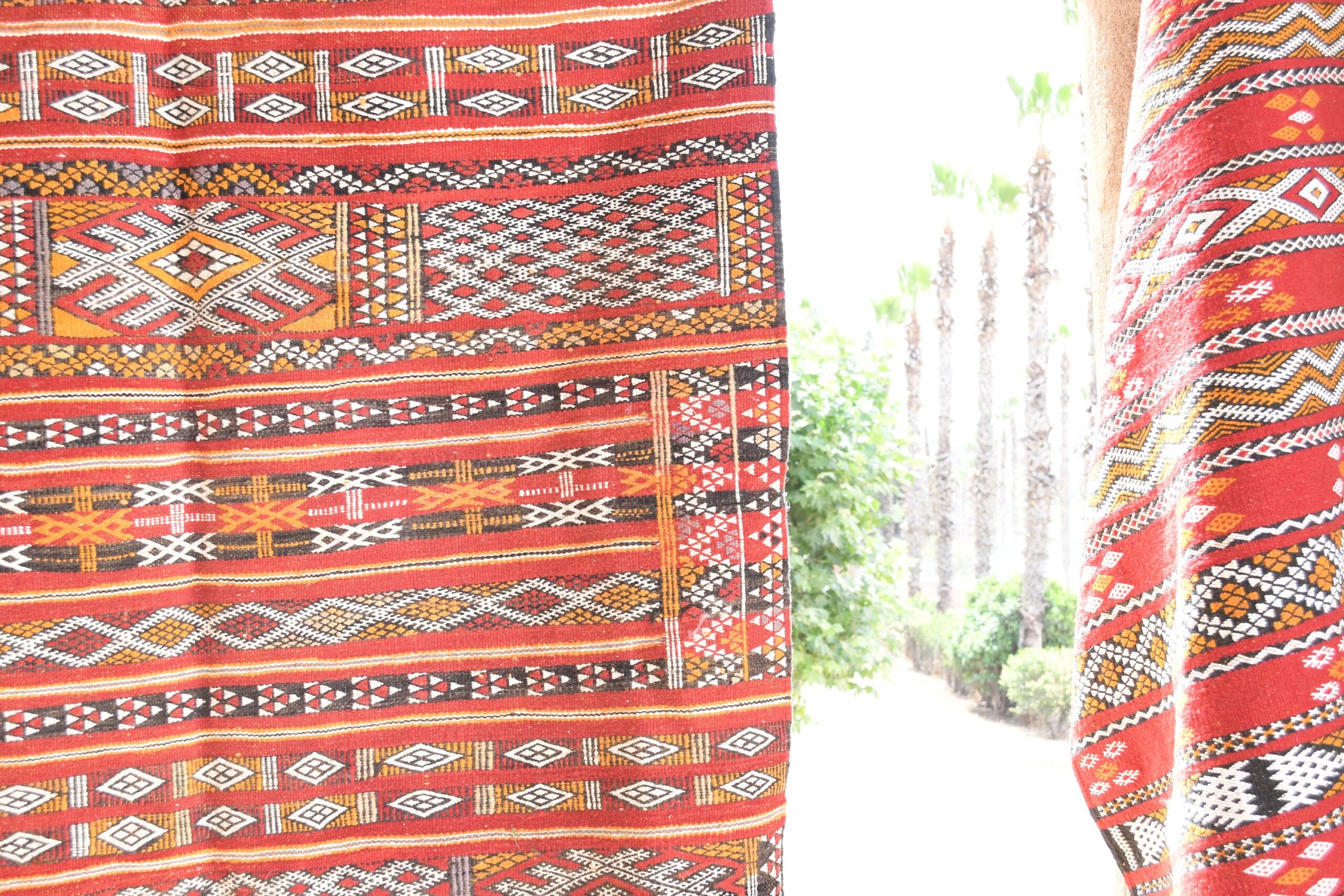 a red and white moroccan rug hanging on a wall. il_fullxfull.6017572086_4xjt.jpg