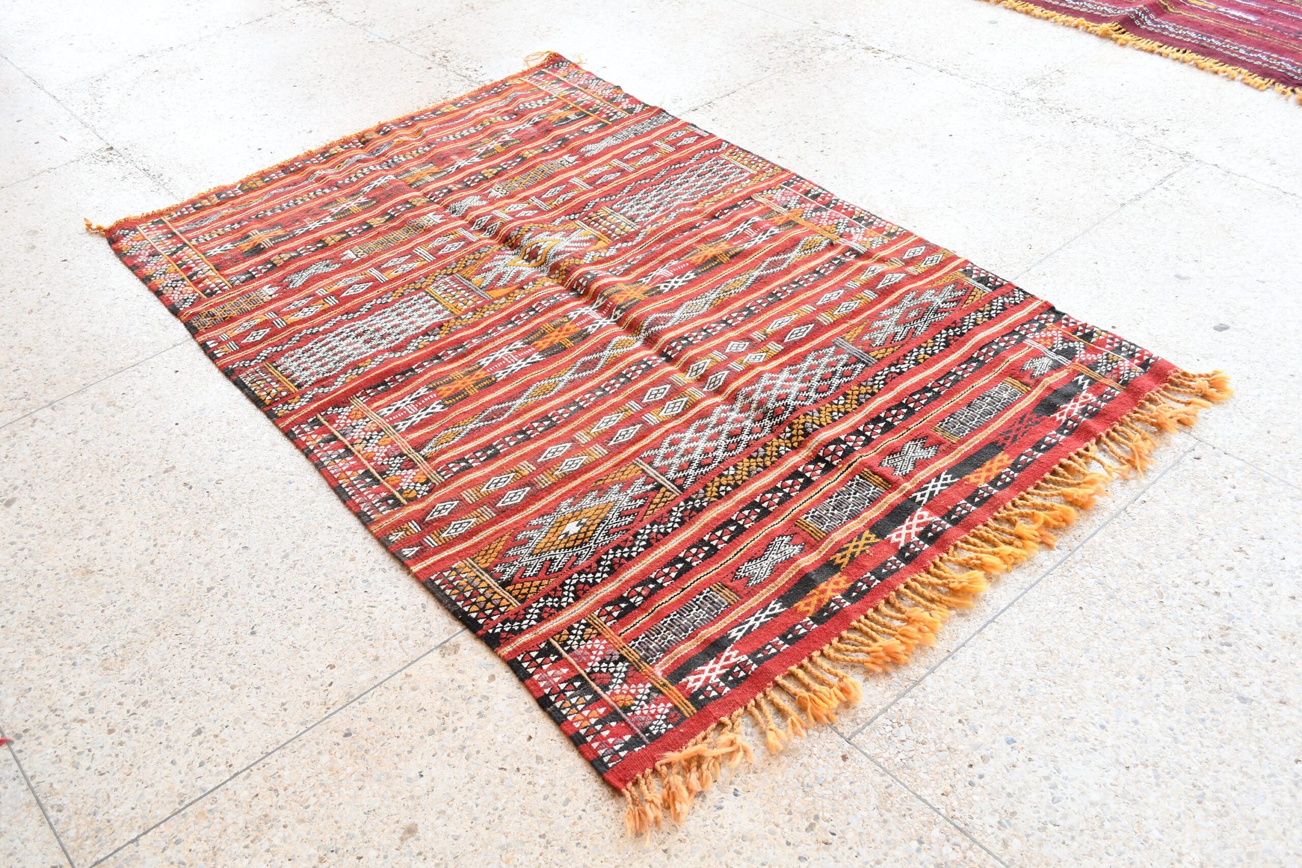 a red and black rug with fringes on the floor. il_fullxfull.6017573816_265k.jpg