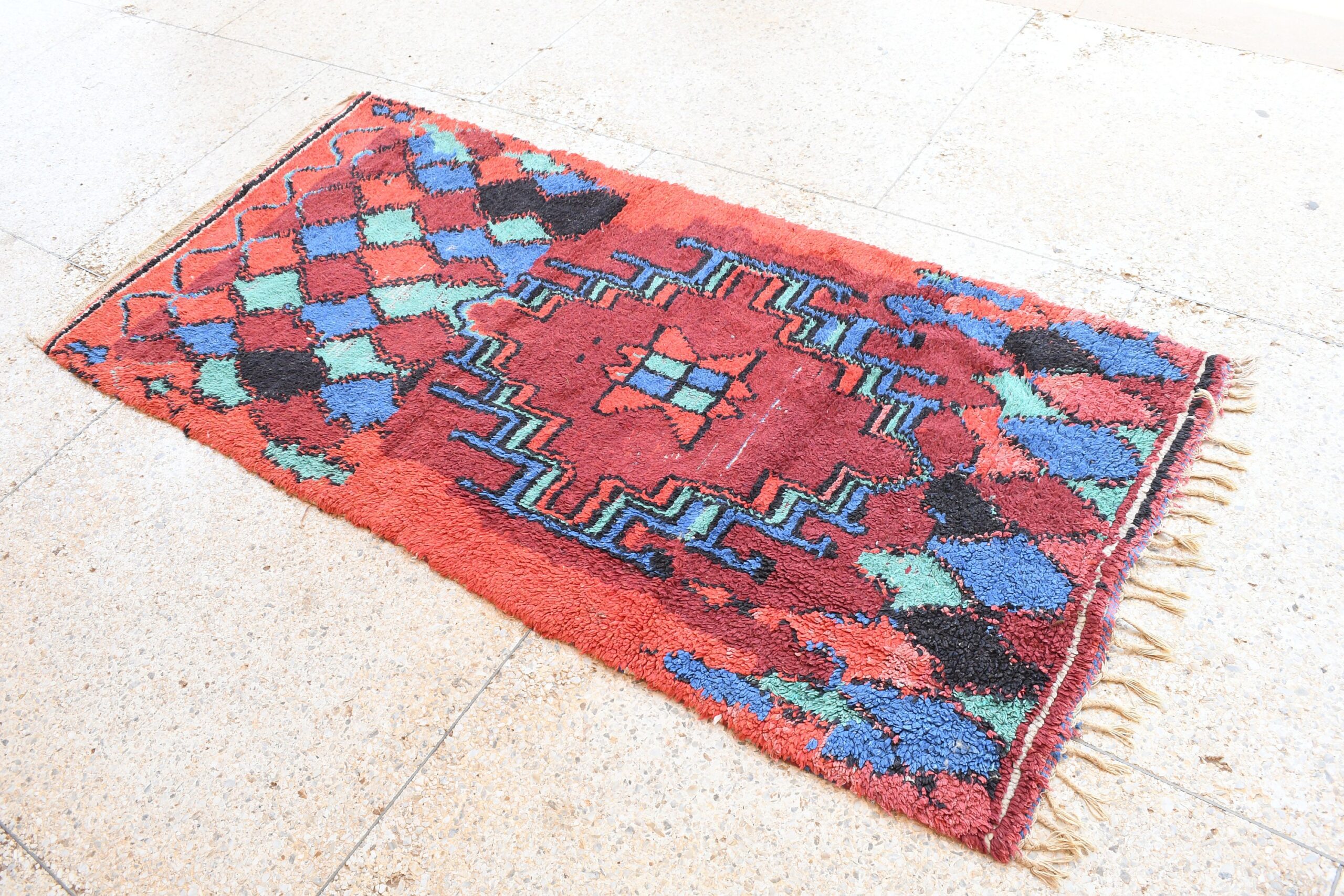 a red rug with a blue and green design. il_fullxfull.6028232480_husm.jpg